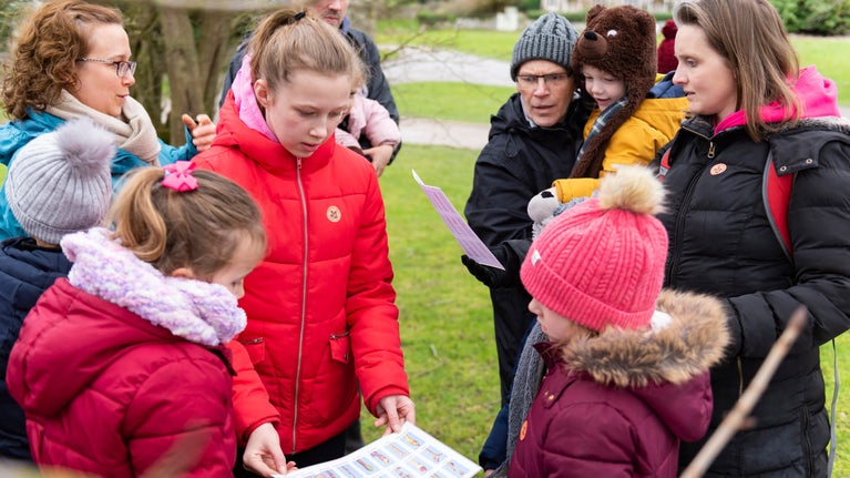 A group of children, looking at a printed guide, learn how to identify wildlife